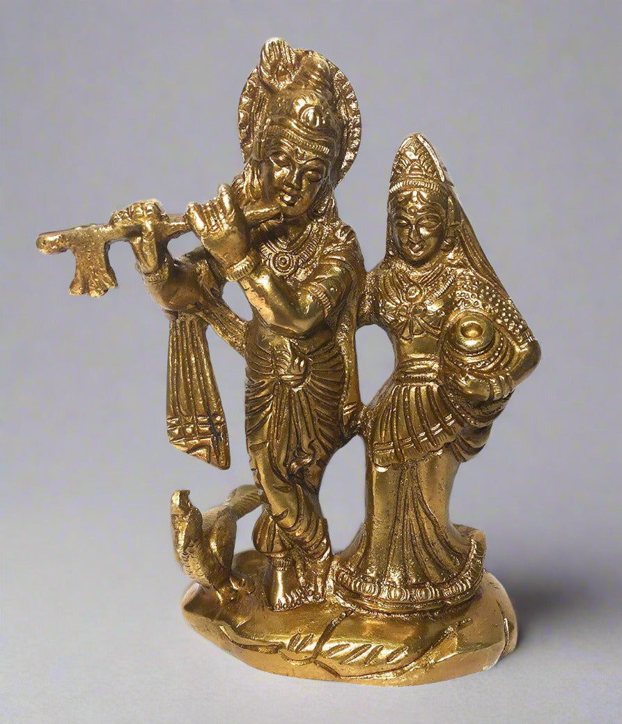 Bronze statue of a deity playing a flute with another figure on a white background