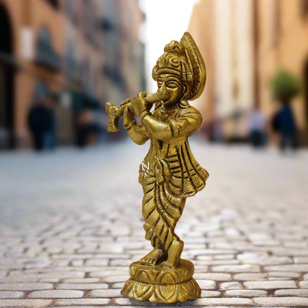 Gold-colored figurine of a deity playing a flute on a wooden surface with 'Prachin Art & Crafts' branding.