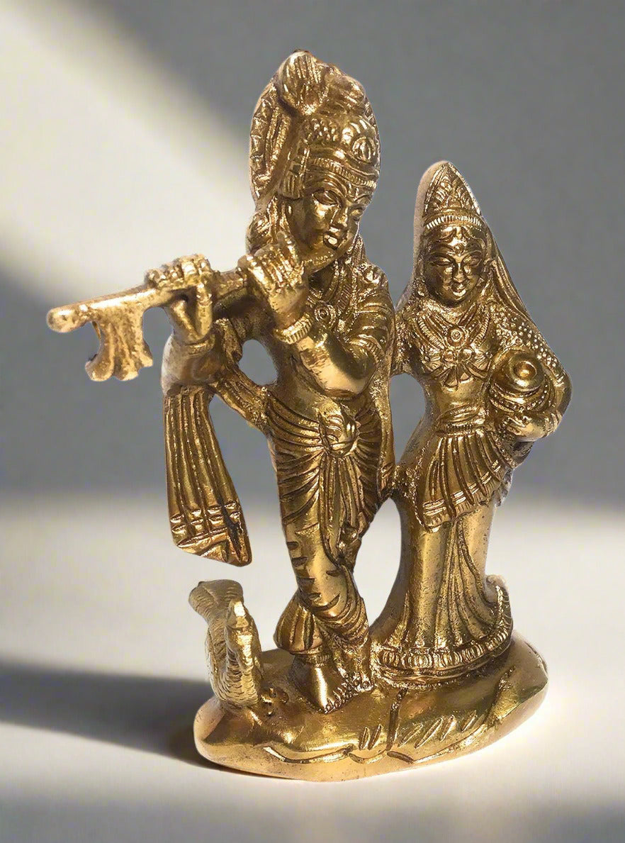 Gold-colored statue of a couple with traditional attire on a white background